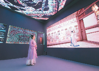 第十九屆中國（深圳）國際文化產(chǎn)業(yè)博覽交易會設(shè)立了“數(shù)字中國——AI時代的文化創(chuàng)新”主題展區(qū)。一批大數(shù)據(jù)、人工智能等技術(shù)應(yīng)用文化企業(yè)參展。數(shù)字化助力中華傳統(tǒng)文化“活”起來，也為現(xiàn)場觀眾帶來了新鮮的觀展體驗。   圖為一名身著傳統(tǒng)服飾的觀眾在文博會甘肅展臺觀看數(shù)字敦煌展覽。   新華社記者 梁 旭攝