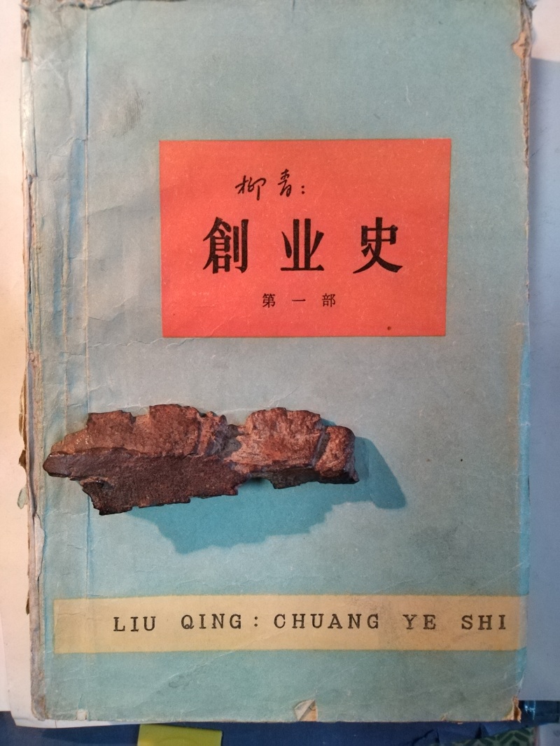 長篇小說《創(chuàng)業(yè)史》（第一部）書影與柳青曾收藏的彈片。 （文金 攝）