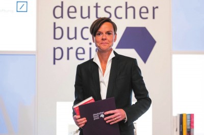     作家安特耶·拉維克·施特魯貝爾在2021年德國圖書獎(jiǎng)?lì)C獎(jiǎng)典禮上手持《藍(lán)色女人》和獲獎(jiǎng)證書。攝影：托馬斯·洛內(nèi)斯